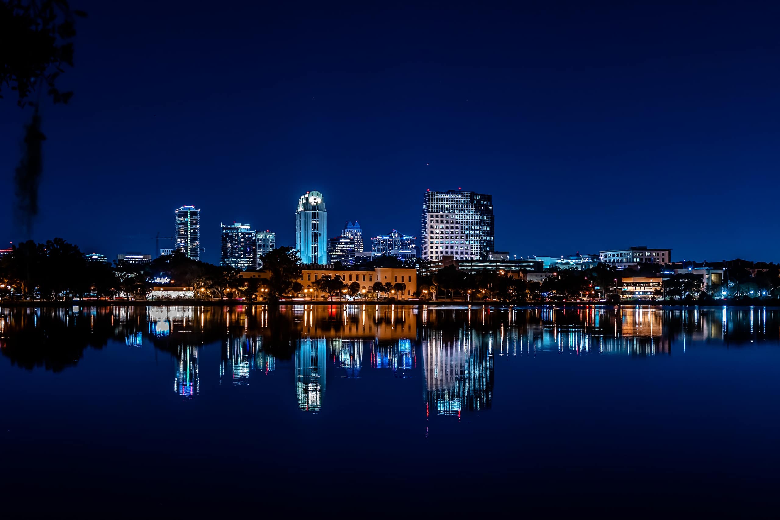 The downtown Orlando skyline reflected in the calm waters of Lake Ivanhoe during blue hour.