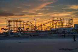 Last Ride The Sand Blaster roller coaster silhouetted against a golden sunset at the Daytona Beach Boardwalk before its removal.